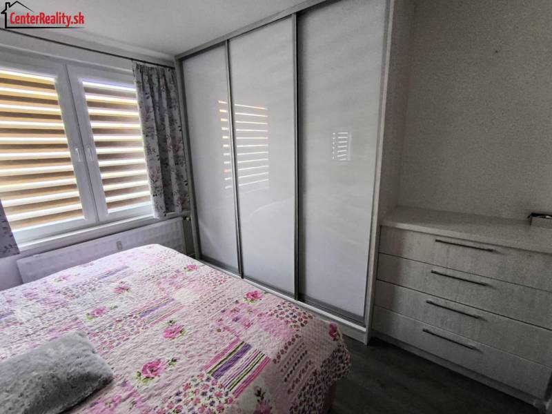 A bedroom with a built-in wardrobe and a floral bedspread in a 3-room apartment.