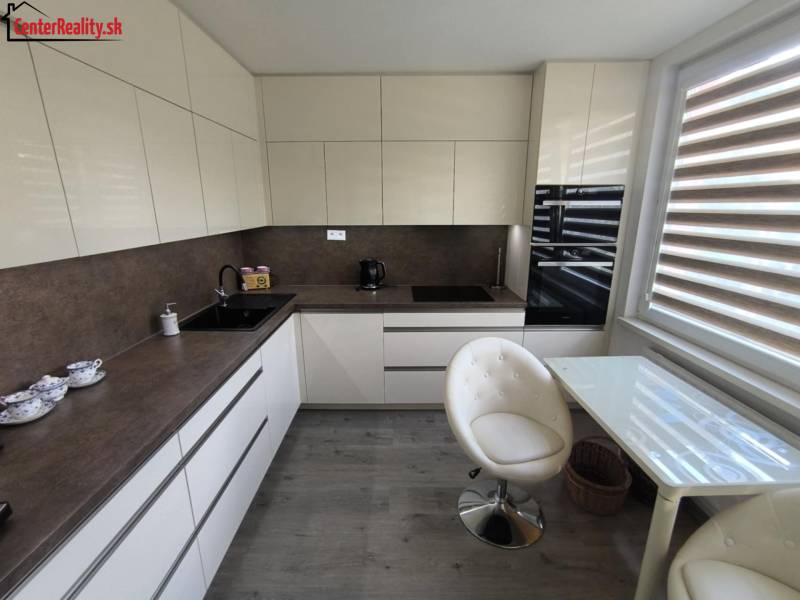 A kitchen in a 3-room apartment with light furniture, a glass table, and two chairs.