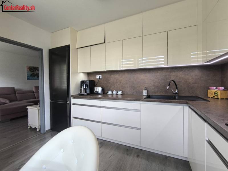 A kitchen in a 3-room apartment with modern equipment and an adjoining living room, light tones.