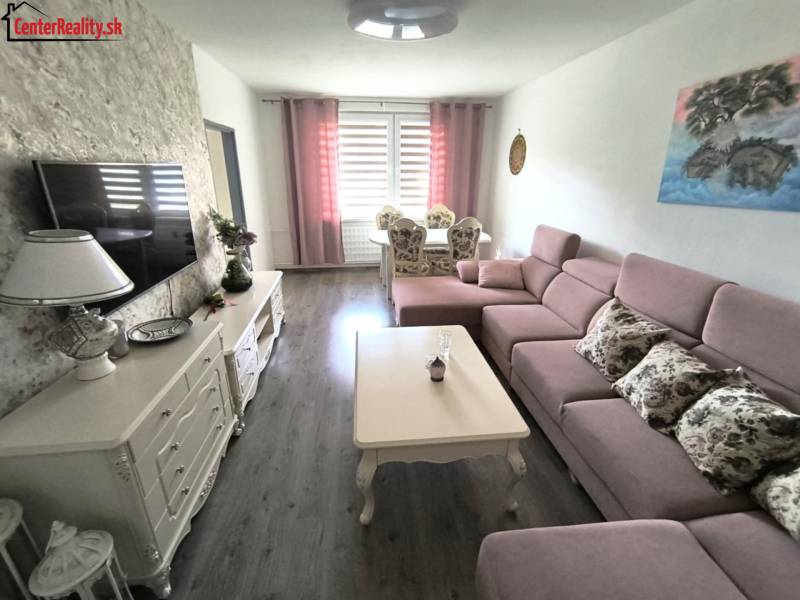 Living room in a 3-room apartment with a pink sofa, table, and decorations on the sideboard.
