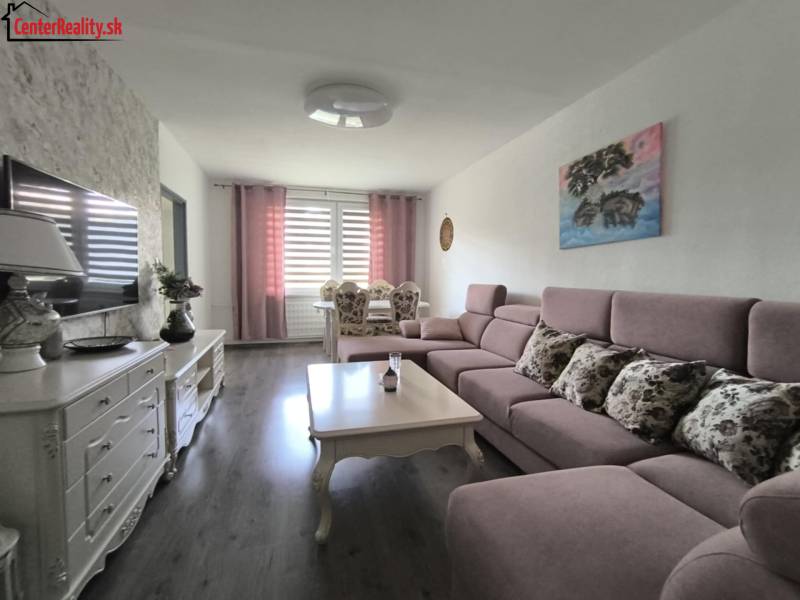 Living room with a sofa and a table in a 3-room apartment, light walls, TV on a cabinet.