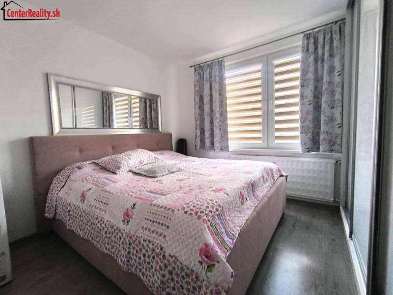 A bedroom in a 3-room apartment with a large bed and a floral bedspread.