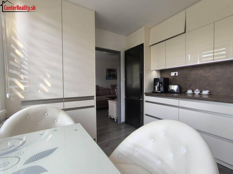 A kitchen in a 3-room apartment with white cabinets and a dining table.