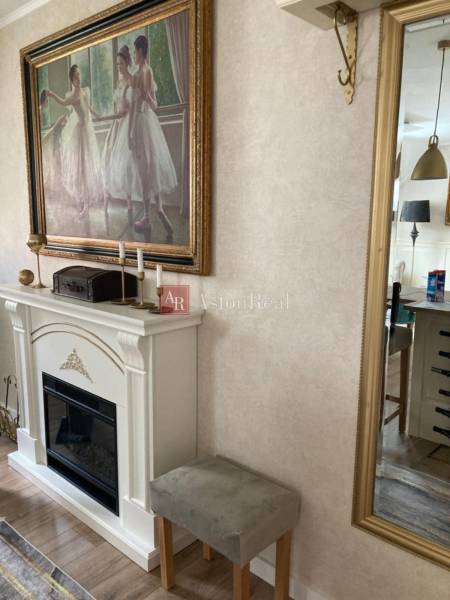 Living room in a 2-room apartment with a stylish fireplace, a painting of ballerinas, and a large mirror.