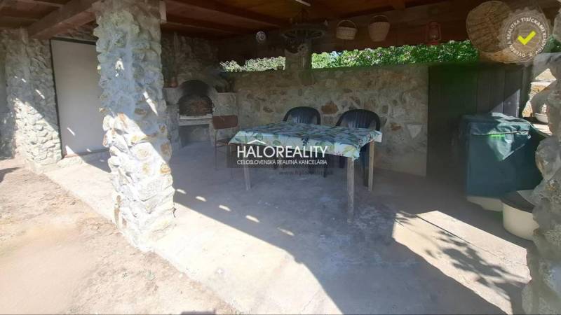 In Klížska Nemá, there is an outdoor seating area with stones and a table by a family house.