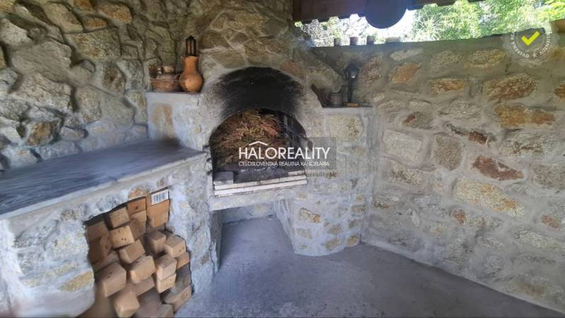 A stone fireplace in the interior of a family house, surrounded by woods and ceramic decorations.