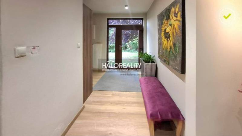 A hallway in a family house with a painting of sunflowers and a purple bench.