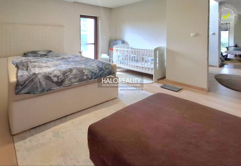 A bedroom in a family house with a double bed, a baby crib, and a light-colored floor.