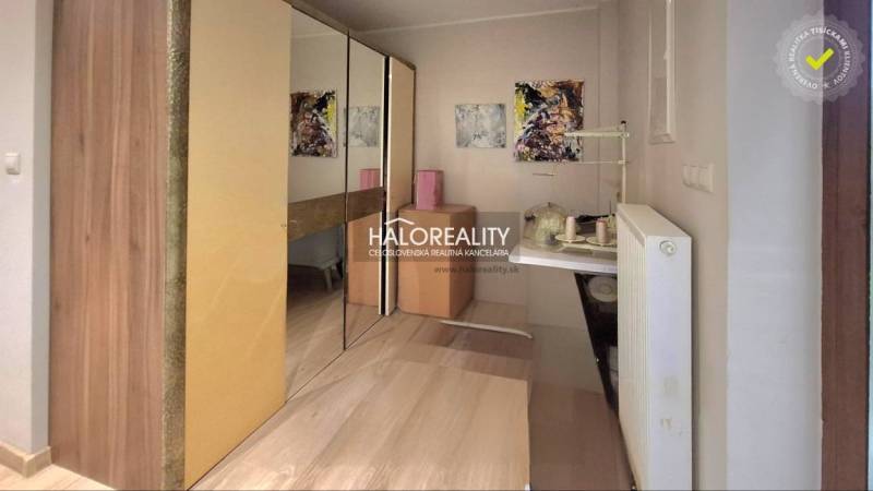 A hallway with wooden furniture, a mirrored wardrobe, paintings, and a radiator in a family house.