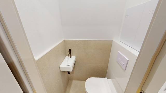 Compact toilet with a sink in a 2-room apartment, beige tiles and white wall.