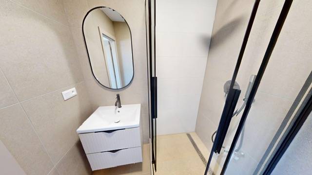 Bathroom in a 2-room apartment with a mirror, sink, and shower corner.