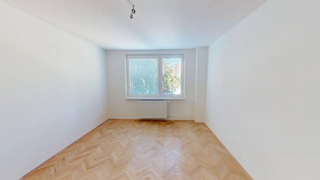 A room with parquet floors in a bright 2-room apartment, a window with a view of trees.
