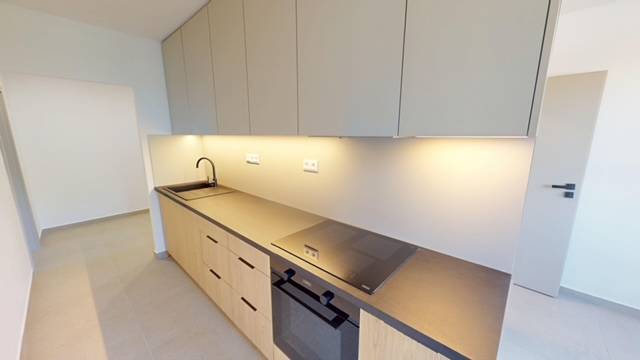 A kitchen in a 2-room apartment with a modern countertop and built-in appliances.