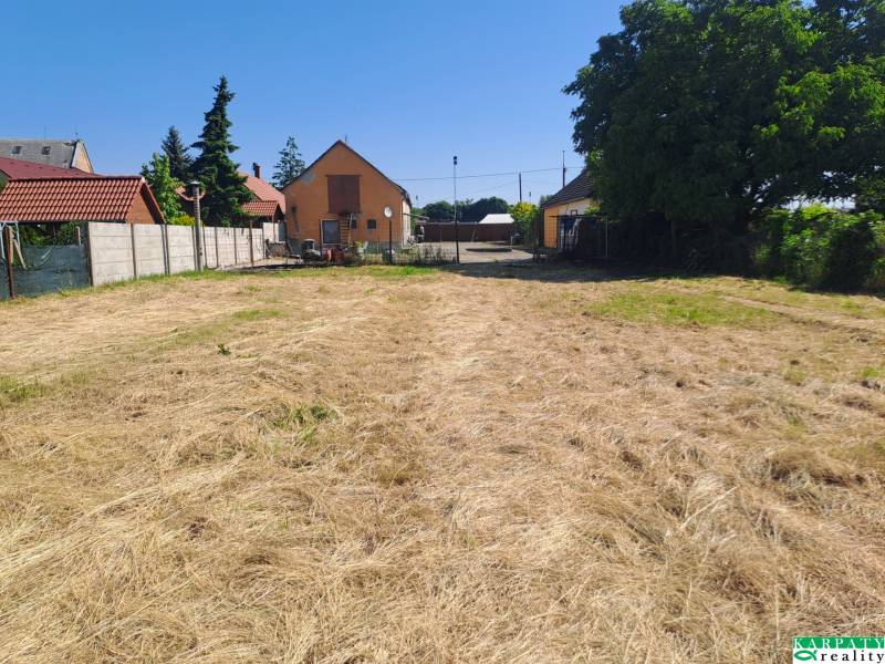 A garden at a family house in Sládkovičovo with a manicured lawn and a fence.