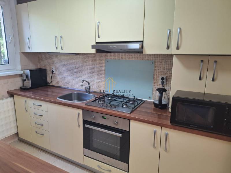 Kitchen in a 3-room apartment with a gas stove and sink, wooden countertop.