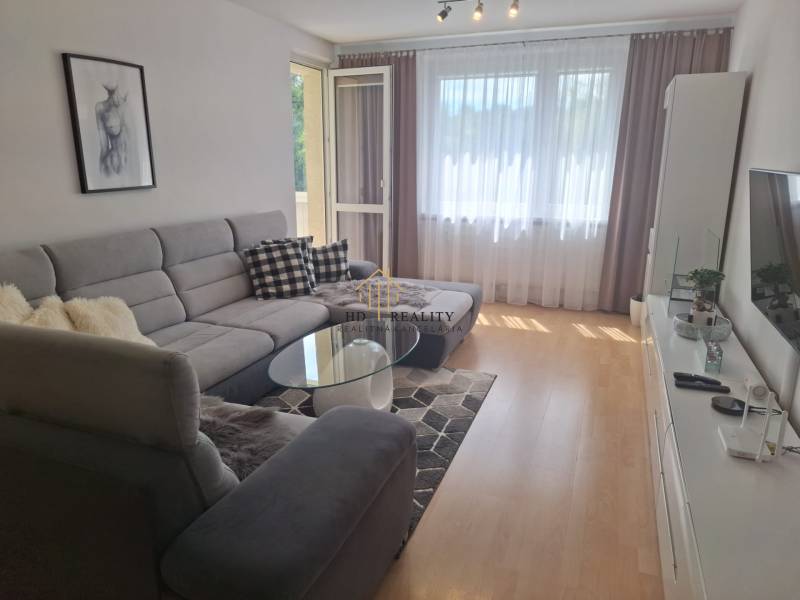 A comfortable living area with a large sofa and glass doors in a three-room apartment.