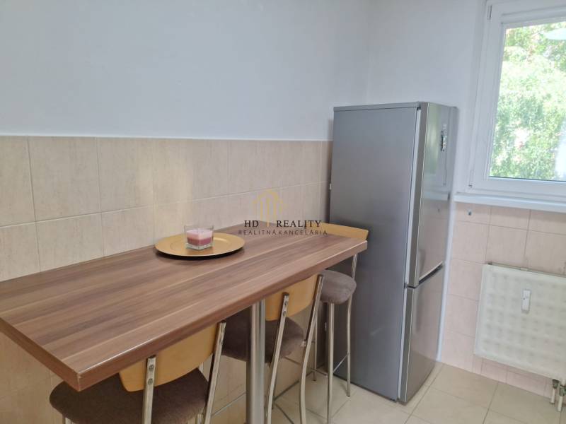 A kitchen with a bar table and a refrigerator in a 3-room apartment.