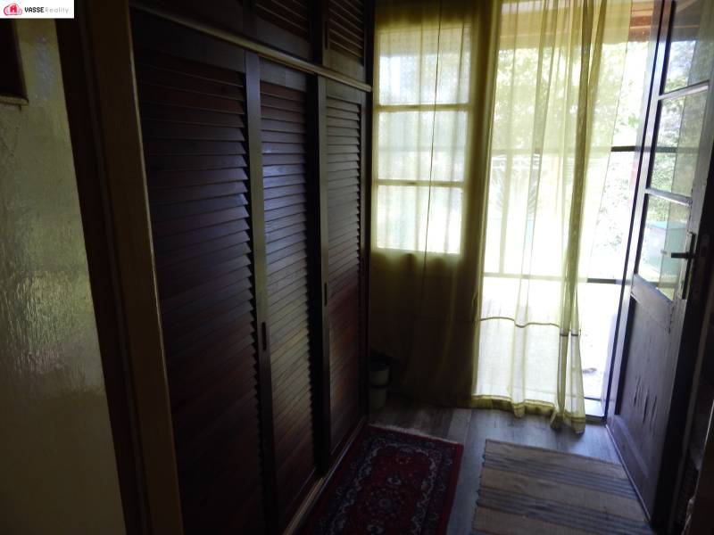 A cottage with a wardrobe, curtains, and rugs offers a cozy interior with a view.