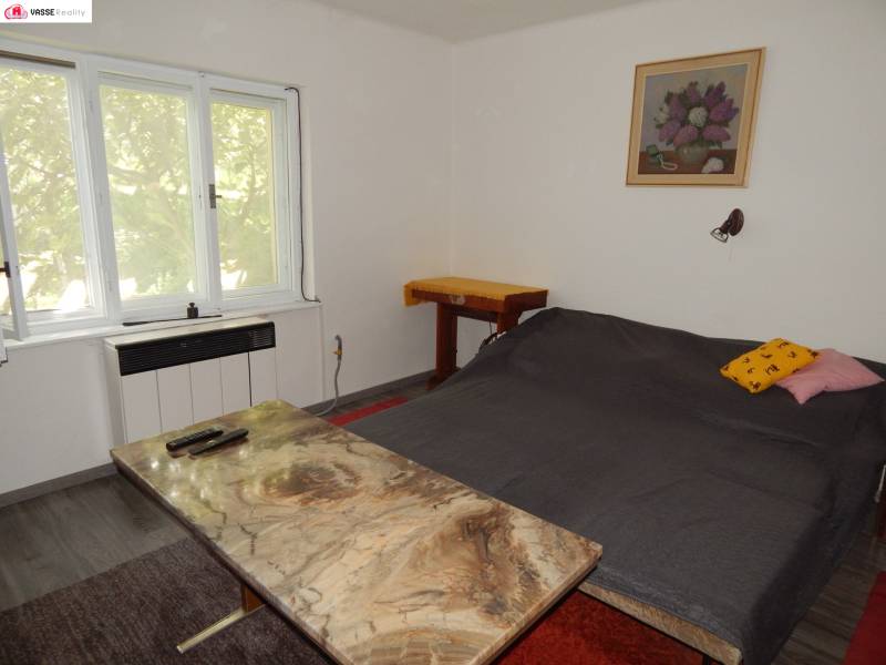 The cottage offers a cozy bedroom with a double bed, a table, and a chair.