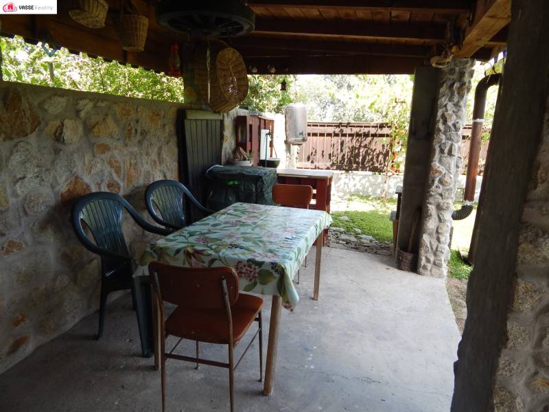 Stone terrace at the cottage in Klížska Nemá with a table and chairs under a shelter.