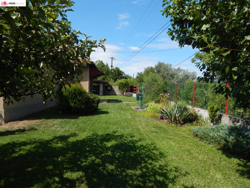 The garden of the cottage in Klížska Nemá surrounded by greenery and a blue sky.