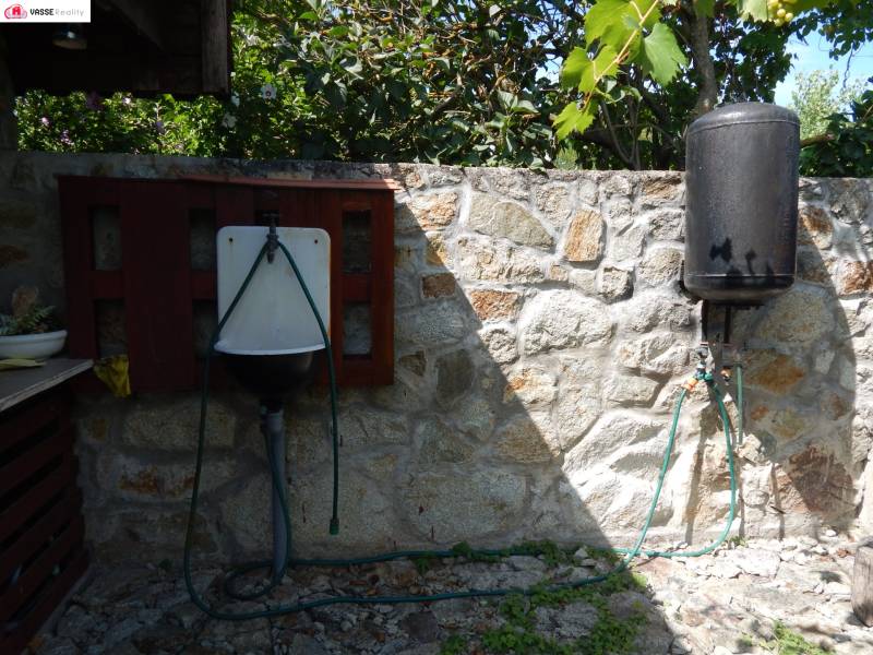 Stone wall in Klížska Nemá with a sink and a tank near the cottage.