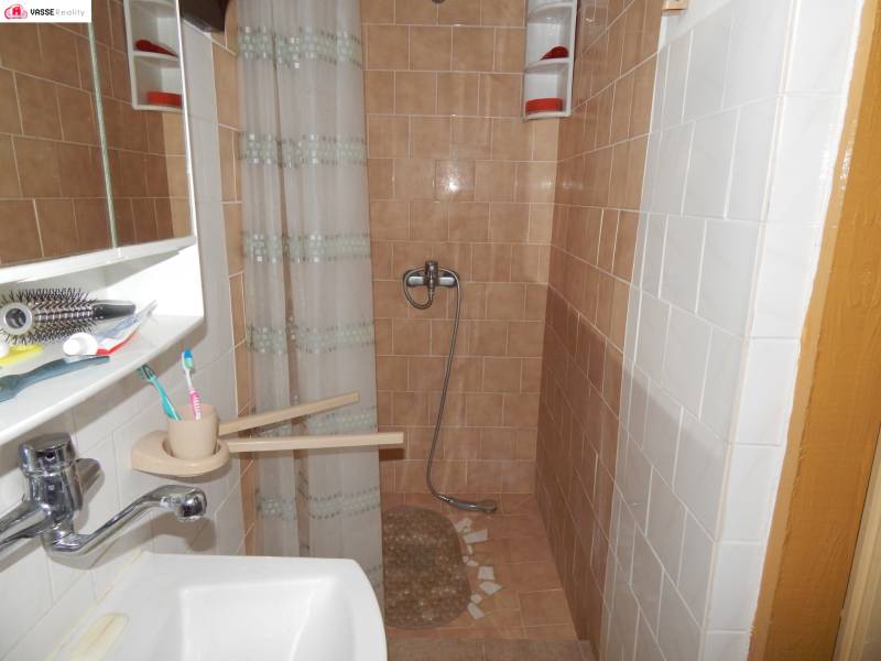 A bathroom in a cabin with brown tiles, a shower, and a sink.