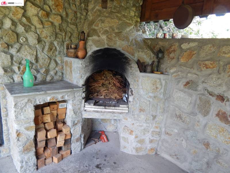 A stone fireplace in a cabin with wood stored in a stone alcove.