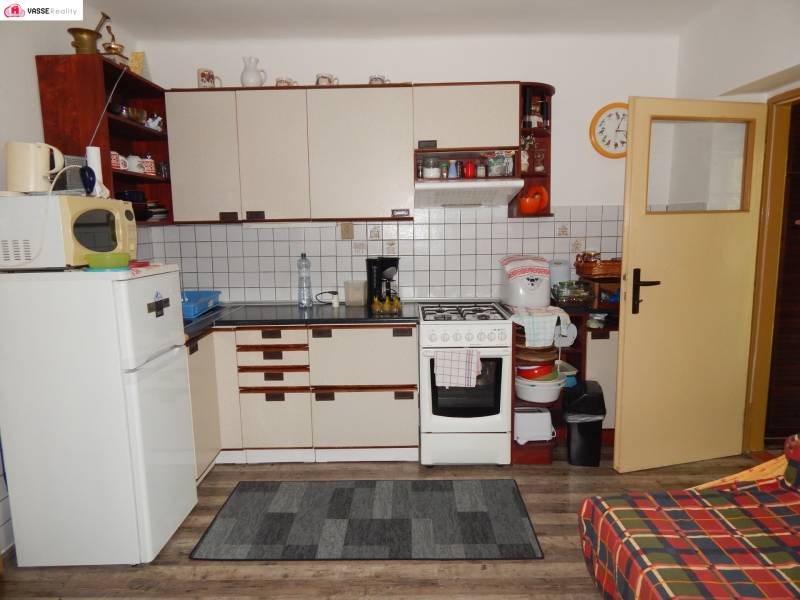 A kitchen in a cabin with wooden floors, cabinets, and appliances.