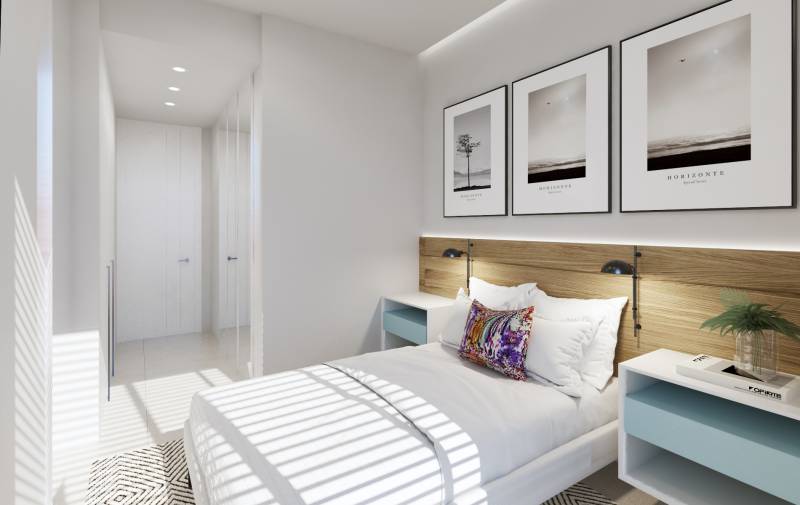 A bright bedroom in a three-room apartment with white furniture and decorative pictures on the wall.