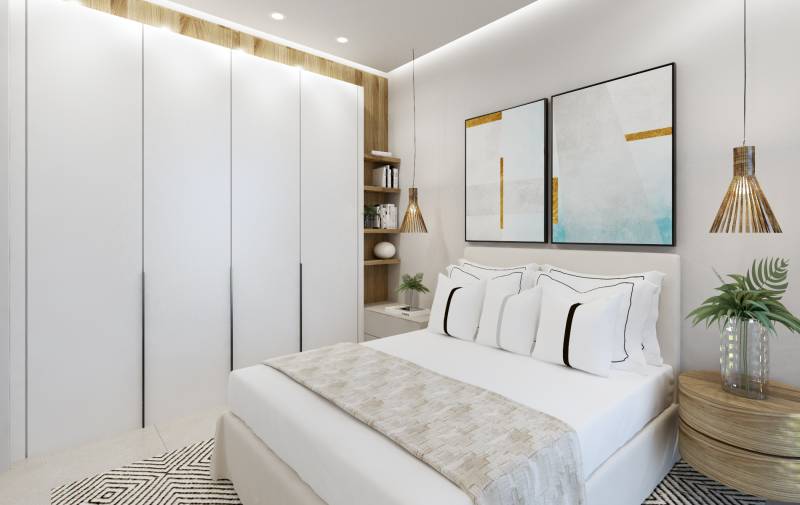 Bright bedroom in a 3-room apartment with white wardrobes and colorful paintings.