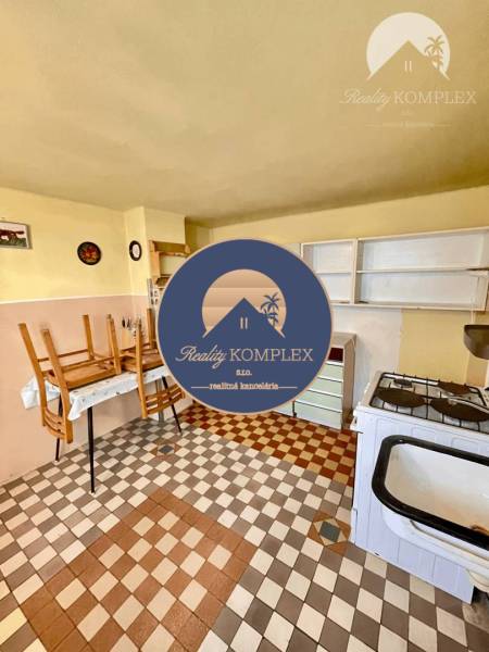 A kitchen in a family house, with an older stove and chairs on the table.