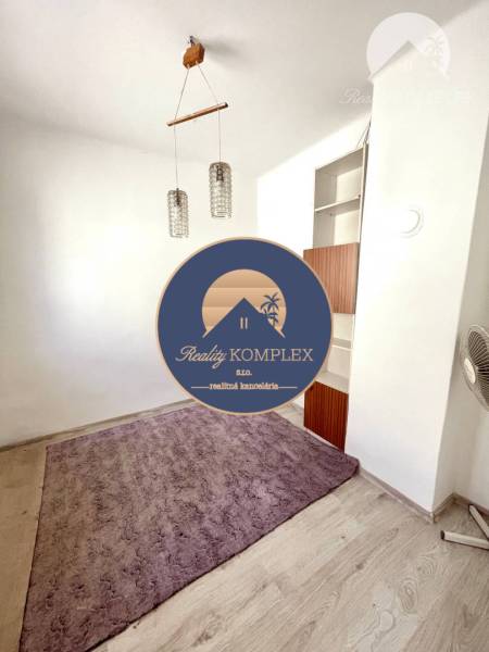 A room in a family house with a purple carpet, a wooden light fixture, and a built-in shelf.