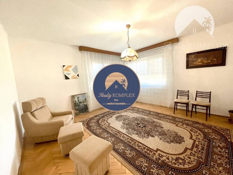 Living room in a family house with an armchair, pictures on the walls, and a patterned carpet.