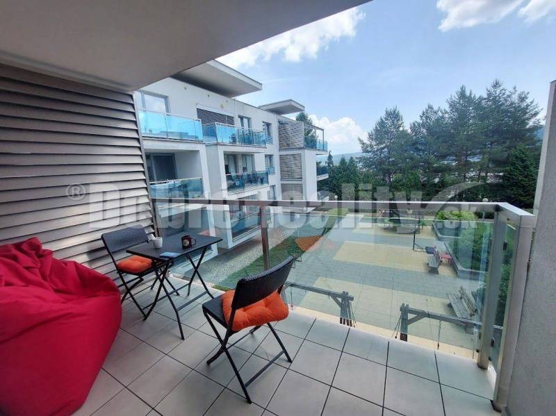 A balcony in a 2-room apartment in Banská Bystrica with a view of the courtyard and trees.