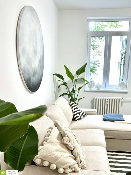 Bright living room of a two-room apartment, comfortable sofa, decorative pillows, houseplants.