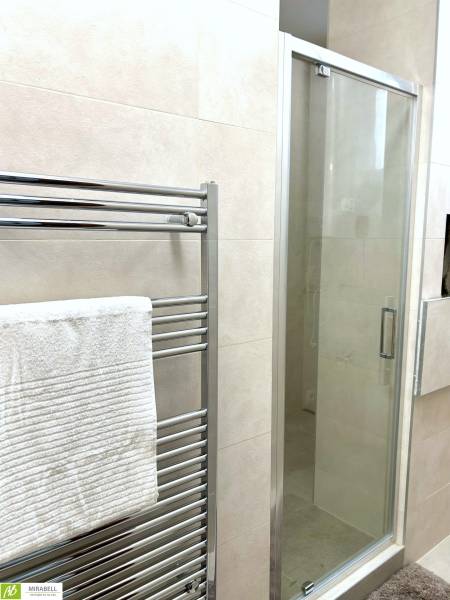 A bathroom with a shower and a ladder radiator in a 2-room apartment.