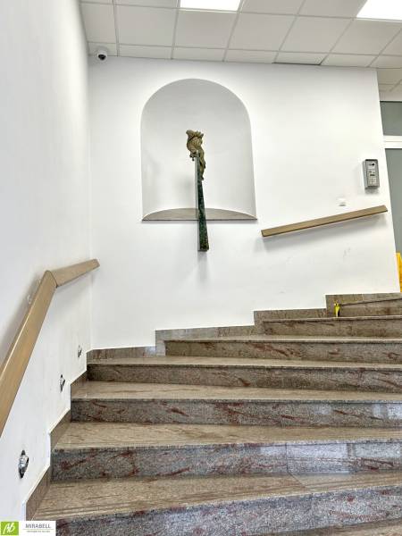 A staircase with marble steps, a railing, and a niche with a statue on the wall.