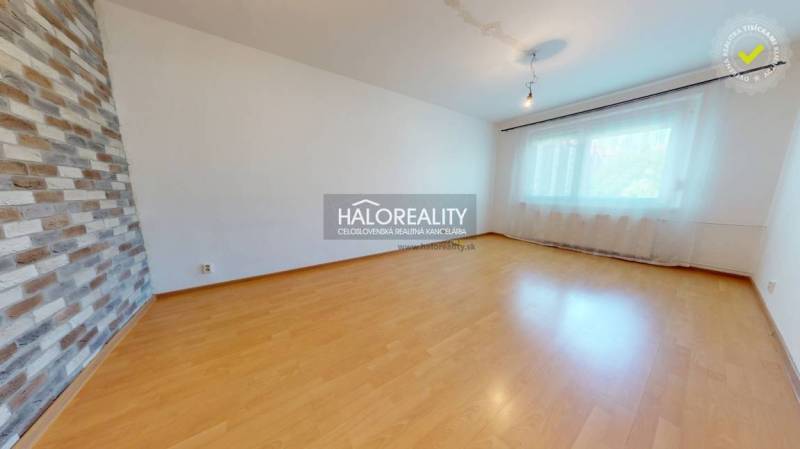 A room with a wooden floor and a brick wall in a 4-room apartment.