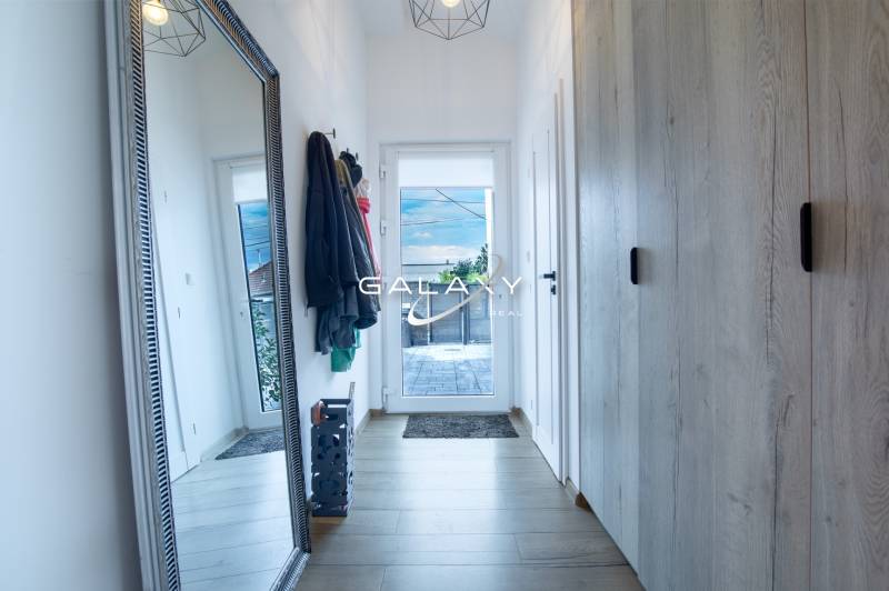 Hallway in a family house with a large mirror, coat racks, and a wardrobe.