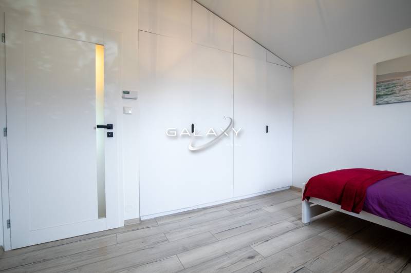 Bedroom in a family house with a white wardrobe, doors, and a bed with a colorful blanket.