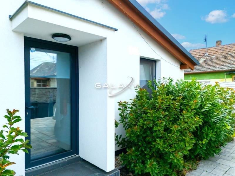 In Čierna Voda, there is a family house with a white facade surrounded by green shrubs.
