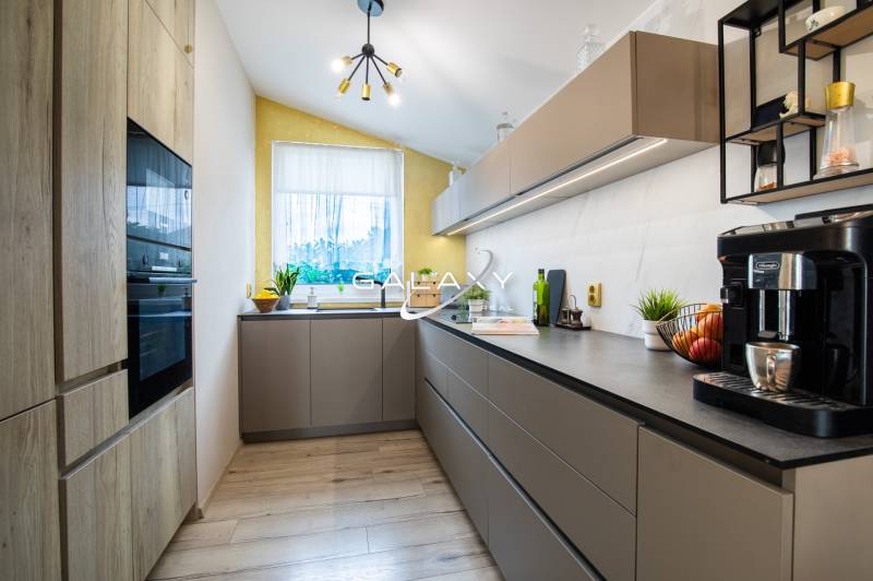 A kitchen in a family house with modern cabinets, appliances, and a bright window.