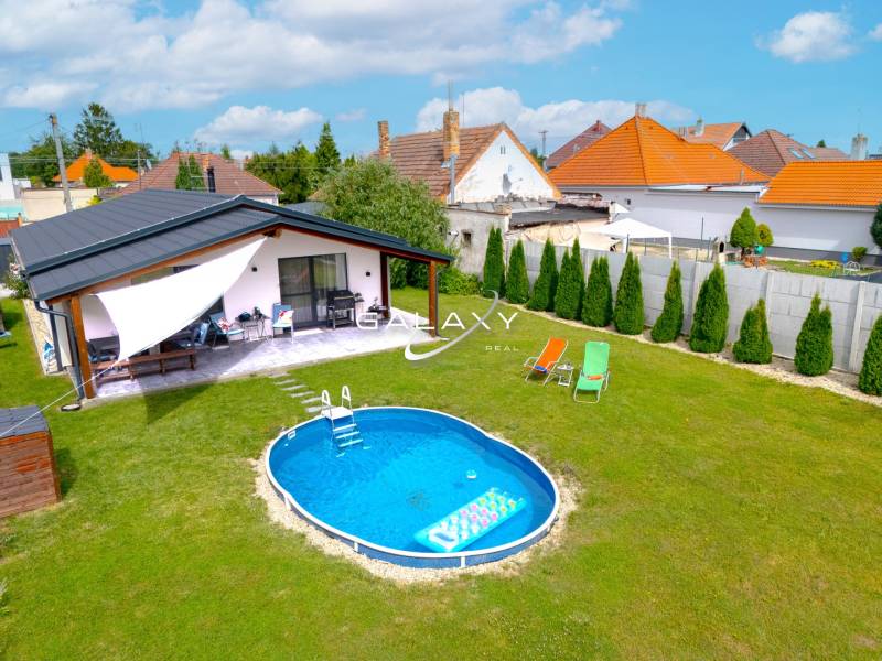 A family house in Čierna Voda with a swimming pool on a green lawn and a terrace.