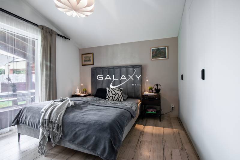 Bedroom in a family house with a bed, nightstands, and lamps, with a view outside.