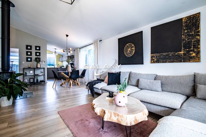 Living room in a family house with a gray sofa, wooden table, and dining area.