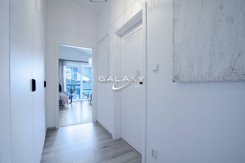 A narrow bright hallway in a family house with a view of the room and terrace.
