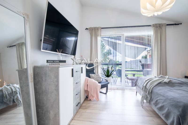 Bright bedroom in a family house with a TV, mirror, and balcony.