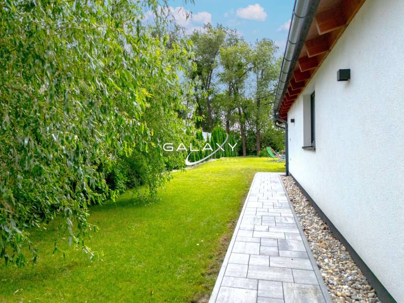 A family house in Čierna Voda with a well-maintained garden and a walkway alongside the building.