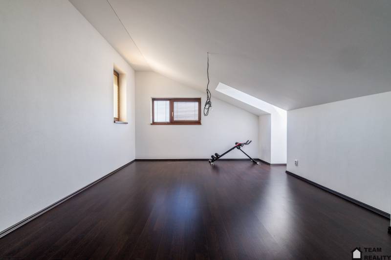 An attic room in a family house with exercise equipment on a dark floor.